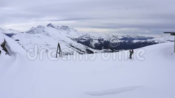 滑雪者骑在雪坡上的滑雪板上在冬季的山上鸟瞰视频的预览图
