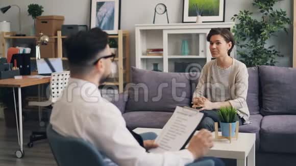 现代办公环境中的中年女性与乐于助人的男性治疗师交谈视频的预览图