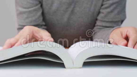 一个学生迅速翻开躺在白色桌子上的书页合上文学封面视频的预览图