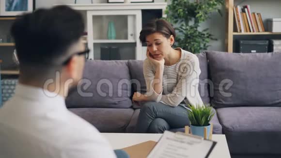 沮丧的女孩和男性治疗师分享问题用不开心的脸说话视频的预览图