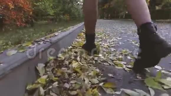 女孩走在满是树叶的路上踢他们视频的预览图