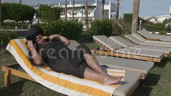 白种人老年女性戴着黑色帽子在阳光下晒太阳躺在一个阳光休息室在一个视频的预览图