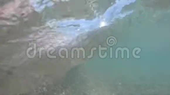 海岸有一个石滩和缓慢的海浪运动与相机浸入水中视频的预览图