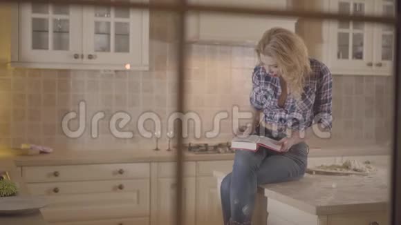 肖像美丽诱人的女孩在厨房的桌子上读一本书充满激情的年轻女人穿着格子花视频的预览图