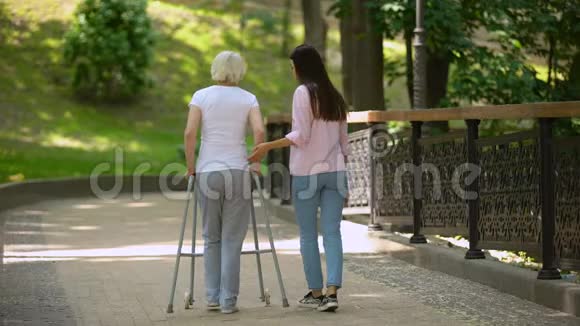在医院公园与使用步行机的老年妇女一起自愿步行视频的预览图