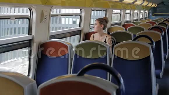 一位美丽的白人女性游客独自坐在空舱地铁列车上望着窗外在她身后视频的预览图