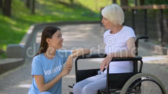 残疾人轮椅上的老年女士与志愿者交谈交谈支持视频的预览图