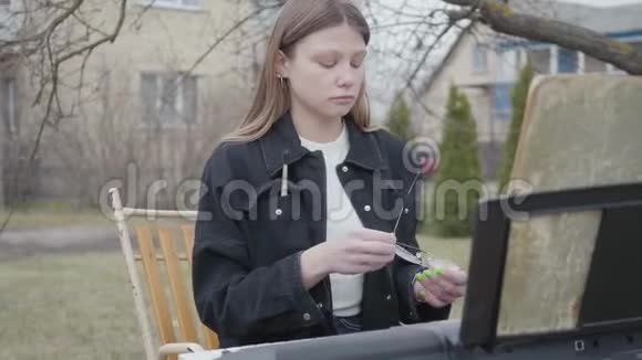 年轻女子戴着眼镜坐在户外的键盘乐器旁有笔记的笔记本放在柜台上视频的预览图