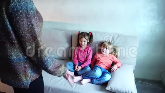 两个女孩坐在沙发上听妈妈关于不良行为的评论视频的预览图