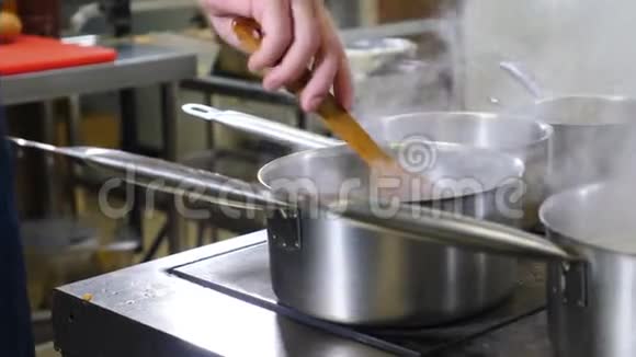 在餐厅厨房拍摄的录像快关门男性用沸水搅拌平底锅做饭太忙了白色蒸汽视频的预览图