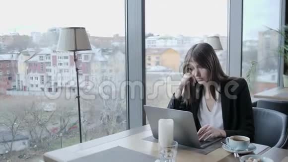 愤怒和严肃的反应年轻女子坐在木桌旁的咖啡店里桌子上有一台灰色铝制笔记本电脑视频的预览图