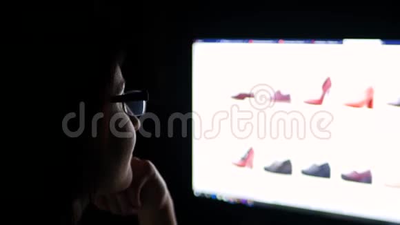晚上一个戴着眼镜的黑发女人在家里用电脑在网上商店买鞋子而在视频的预览图