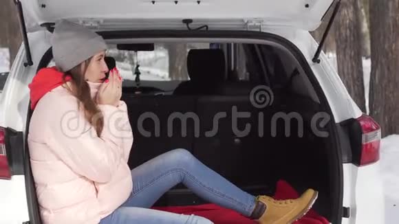一个漂亮的女孩坐在白色的车厢里呼吸温暖双手环顾四周视频的预览图