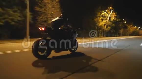 男子骑着现代黑色摩托车在傍晚的城市街道摩托车手在夜间驾驶摩托车视频的预览图