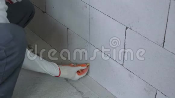 在砌块墙上的钻孔中插入销钉的施工人员的倾斜镜头视频的预览图