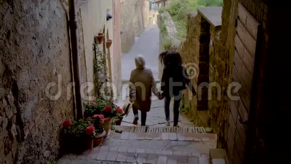后景一个两个女孩走在狭窄的威尼斯街牵着手孩子快乐的女孩视频的预览图