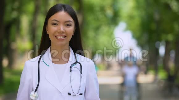 在医院公园里快乐的女治疗师微笑着对着镜头视频的预览图