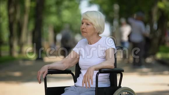 在疗养院公园坐在轮椅上的令人不安的老年妇女身患绝症视频的预览图