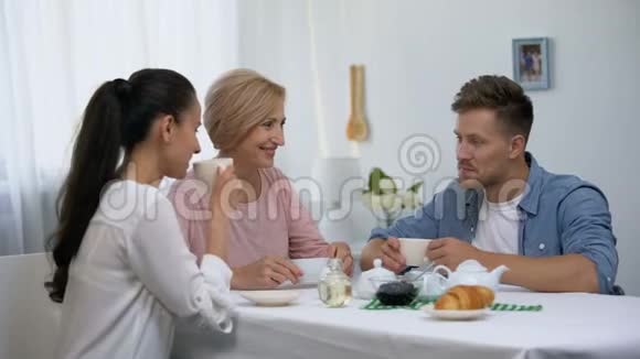 年轻夫妇和婆婆喝着茶真诚地笑着在一起的时间视频的预览图