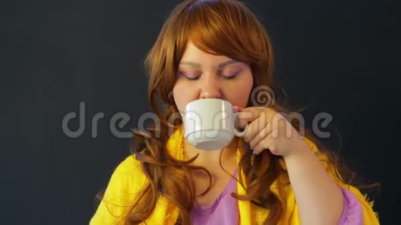 红发女孩在餐桌旁的咖啡馆喝绿茶用勺子吃蛋糕视频的预览图