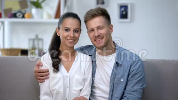 一对幸福的夫妇坐在沙发上双手戴着订婚戒指视频的预览图