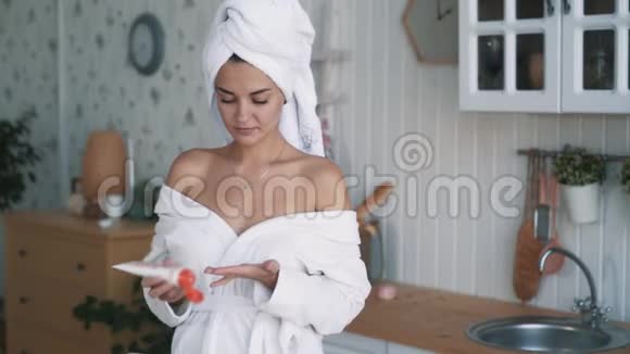 穿着浴袍的漂亮女孩头上有毛巾身体上有奶油动作缓慢视频的预览图