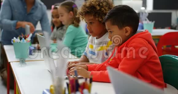 4k教室里在笔记本电脑上学习的混血学童的侧视图视频的预览图