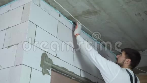 建筑工人用低角度射水从墙上清除过多的安装泡沫视频的预览图