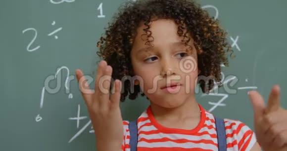 4k教室里用手指对着黑板数着混血女学生的正面景色视频的预览图