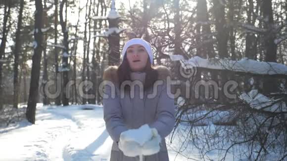 年轻快乐的女人穿着冬天的衣服扔一把雪享受飘落的雪花有魅力的女孩视频的预览图