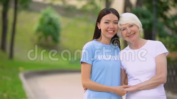 女志愿者和幸福的老太太牵着手微笑相机支持视频的预览图