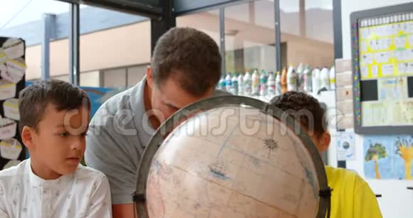 青年白种男教师在4k教室用地球仪教孩子地理的前视图视频的预览图