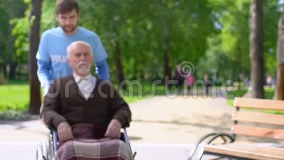 男性志愿者照顾老年残疾患者在公园逗留视频的预览图