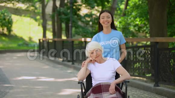 微笑的女志愿者和残疾的老年妇女看着相机慈善机构视频的预览图