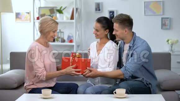 情侣向婆婆赠送红色礼盒家庭关系周年庆视频的预览图