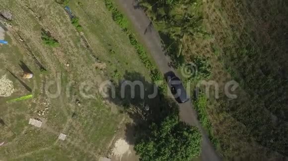 在热带岛屿的公路上行驶的黑色汽车的俯视图棕榈树视频的预览图