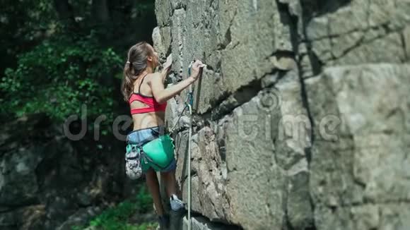 年轻苗条肌肉发达的女子攀岩者在艰难的运动路线上登山者做出了艰难的举动视频的预览图