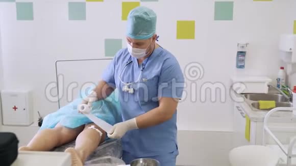 外科手术后无菌衣服包扎病人腿部的医生视频的预览图