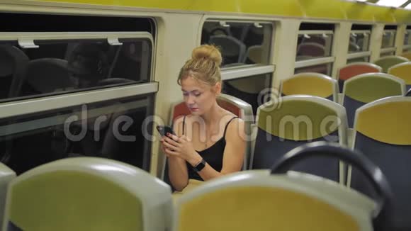 美丽的白种人女游客乘坐空火车穿过黑暗的隧道在一排排座位后面灯光视频的预览图