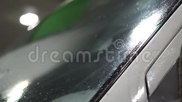 晚上在加油站用旧海绵和棍子清洗汽车玻璃视频的预览图