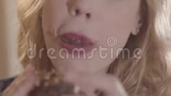 特写肖像年轻美丽的金发女人贪婪地吃甜甜圈舔她的手指视频的预览图