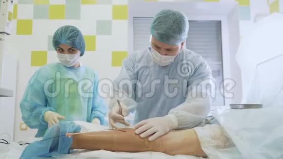 外科医生在硬化手术中穿着无菌衣服刺穿病人的腿视频的预览图