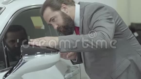 肖像英俊自信长胡子西装革履的商人在汽车经销商处检查新购汽车视频的预览图