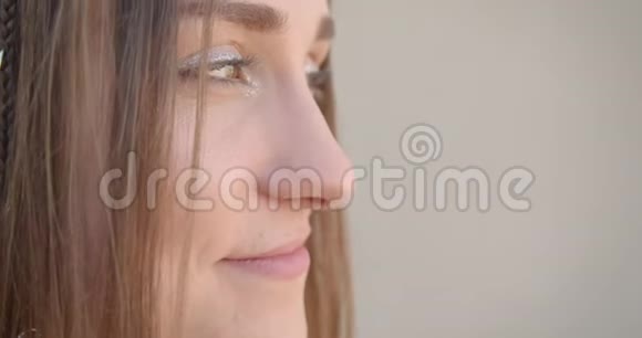 特写侧景拍摄年轻漂亮的白种人女性脸有发环和闪光的妆容眼睛看着视频的预览图