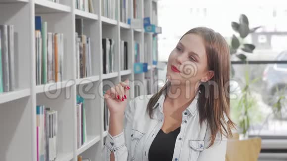 从图书馆书架上选书的年轻女子视频的预览图