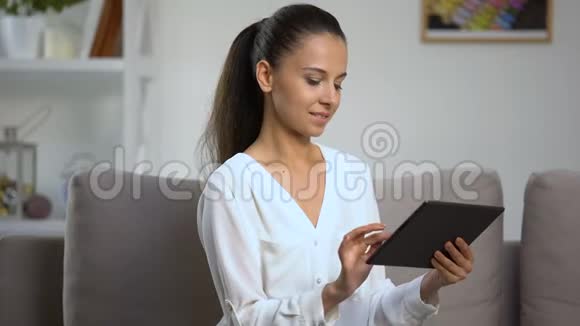 年轻女性在家使用平板电脑看相机社交网络在线视频的预览图