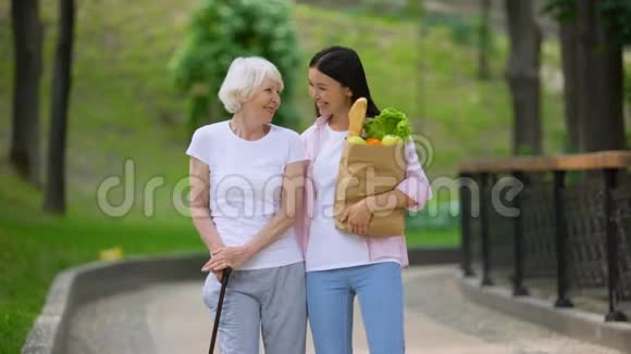 孙女带食物给老年女性病人在医院公园散步视频的预览图