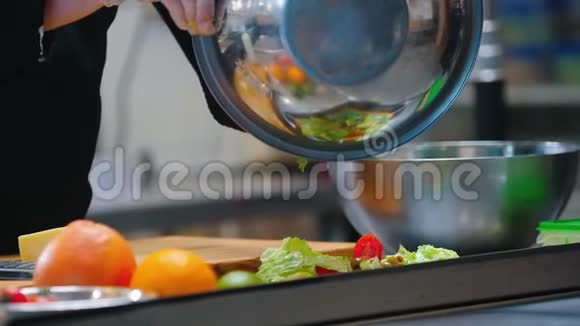 厨房厨师从金属碗里转移蔬菜视频的预览图