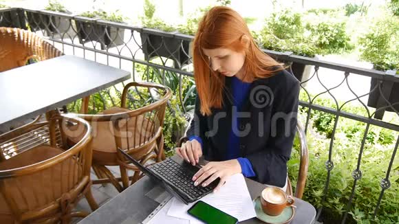 年轻迷人的商务女性在咖啡馆里使用笔记本电脑文件带有绿色屏幕的手机和咖啡杯视频的预览图