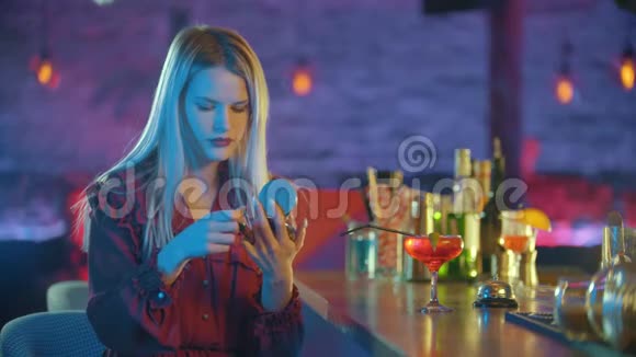 漂亮的年轻女子坐在酒保的旁边嘴唇上涂着红色的口红视频的预览图